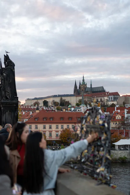 Prague Castle and St Vitus Cathedral beyond Charles Bridge with visitors moving in the foreground.