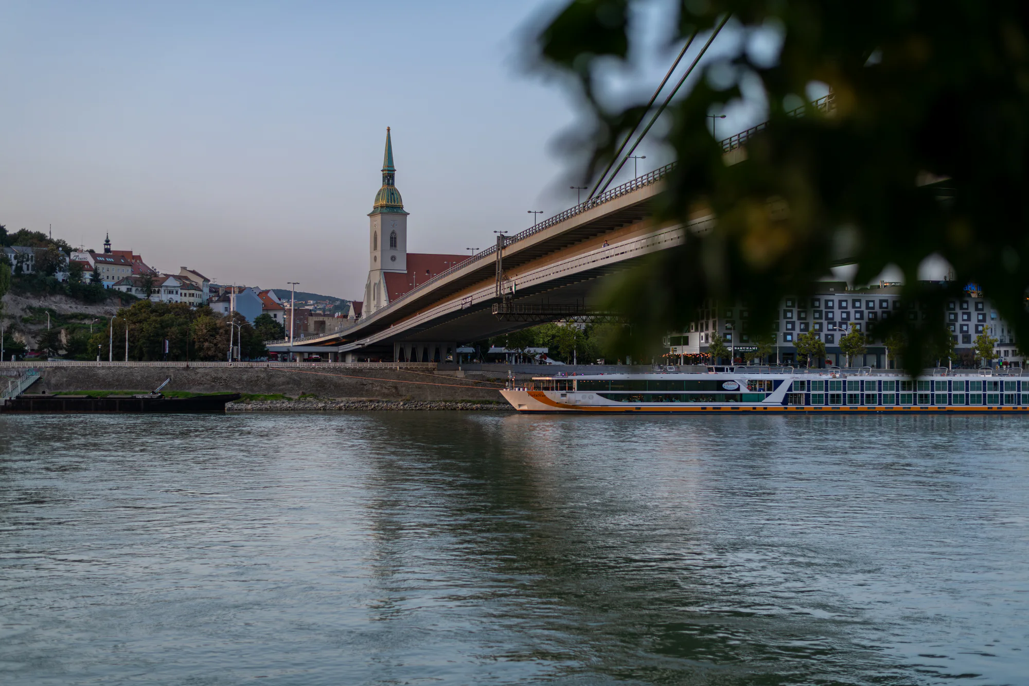 St Martin's Cathedral and the SNP Bridge seen across the Danube with a riverboat in Bratislava.