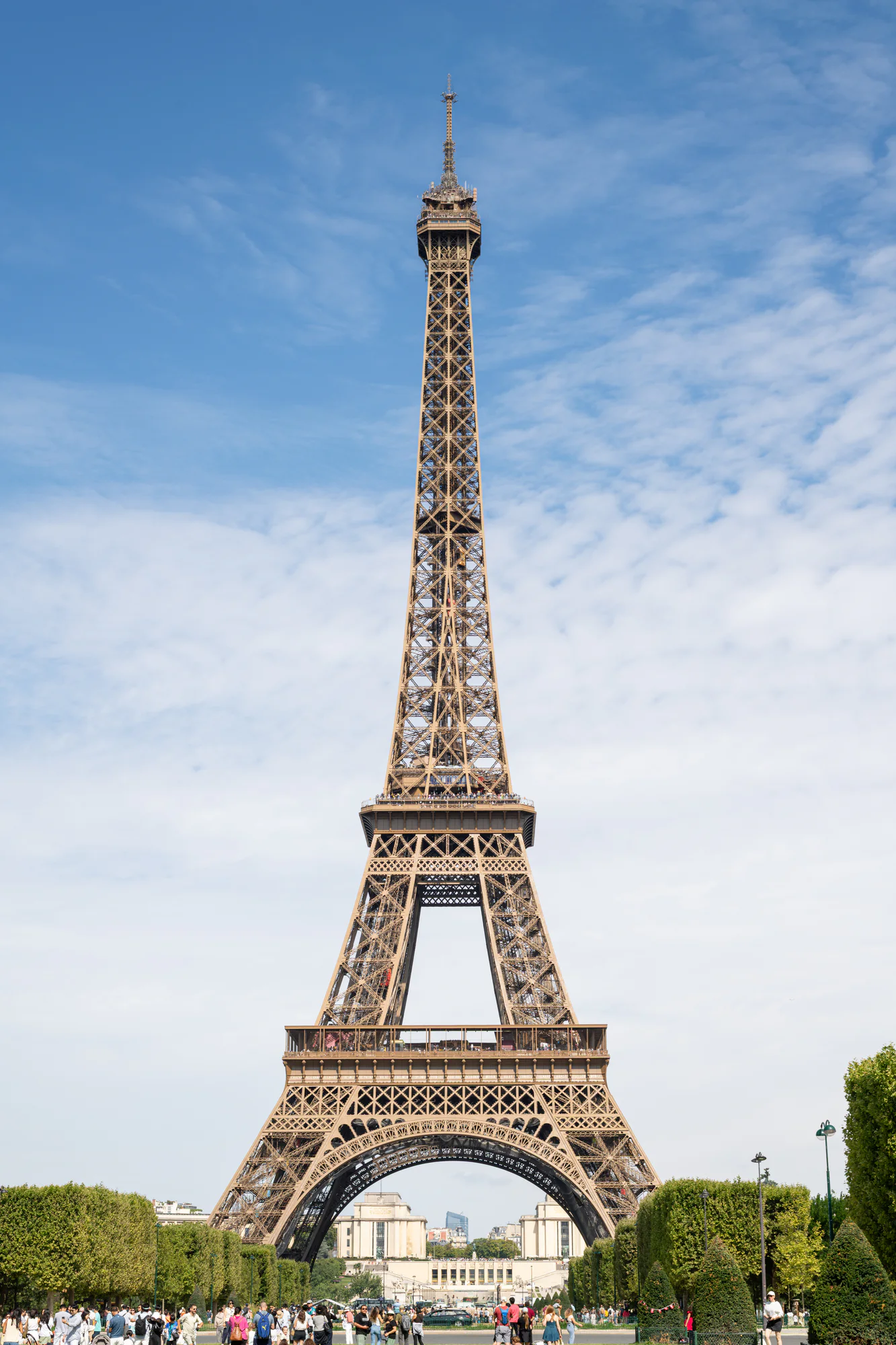 Eiffel Tower rising above the Champ de Mars under a blue summer sky in Paris.